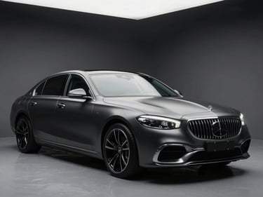 Wide studio shot of a luxury sedan fully wrapped in deep satin charcoal, three-quarter front angle under controlled overhead strobes, the surface tension of the vinyl visible in the sculpted body lines, clean dark background with no distractions