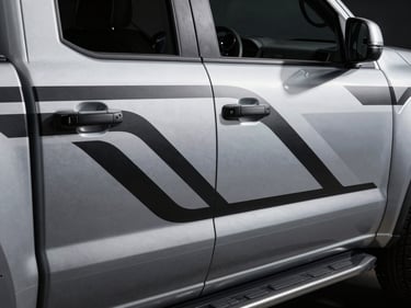 Overhead 45-degree shot of a pickup truck door panel with a precisely applied custom graphic, bold geometric lines in monochrome silver and black, studio strobe lighting sculpting the surface detail, minimal dark background