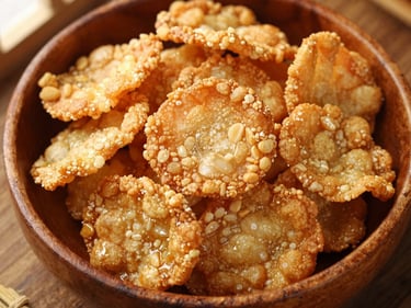 Overhead shot of a rustic wooden bowl filled with crispy, golden-brown fried snacks, perhaps keropok lekor or curry puffs. Warm natural light, rich textures.