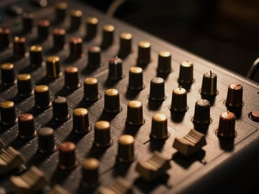 Close-up detail of high-end analog audio console knobs under warm low-key tungsten lighting, deep shadows, elegant cinematic atmosphere, gold and copper accents, 35mm