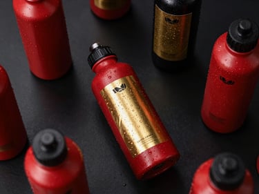 Overhead table layout showing custom-branded corporate water bottles with metallic gold foil labels, dark background.