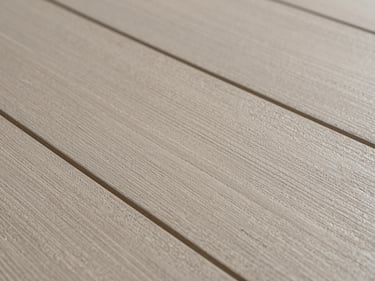 Macro shot of luxury vinyl plank surface texture, stone-effect pattern in warm greige, embossed grain detail catching raking side light, no people