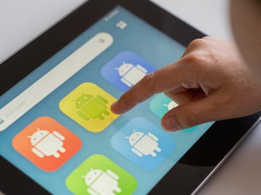 Extreme close-up of a child's finger tapping a brightly colored Android app interface on a tablet, natural indoor daylight, tight frame showing only the screen and small hand