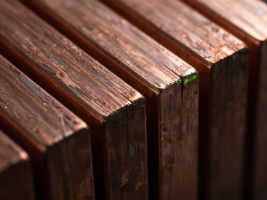 Macro shot of pure copper bars with sharp metallic edges under high-contrast lighting.