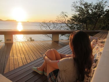 a woman sitting on a couch with a view of the ocean
