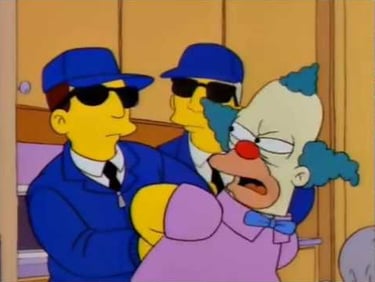 a cartoon character dressed as a clown in a suit and sunglasses