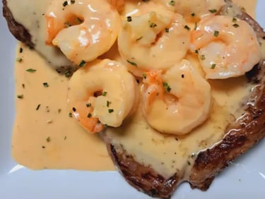 a plate of carne asada with shrimp in seafood sauce