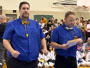 two men standing on a blue mat with a man in a blue shirt