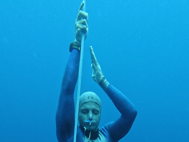 A close up of a Freediver ascending, showing the hands pulling on the dive line