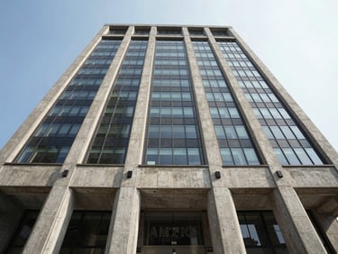 Low-angle perspective of a massive concrete and glass banking headquarters under crisp daylight, emphasizing geometric symmetry.