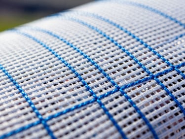 Crisp macro close-up of high-performance technical fabric mesh with vibrant electric blue stitching, bright daylight, sharp focus.