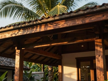 Close-up of a luxury villa interior in Ubud, open-air wooden architecture, soft golden hour sun rays filtering through palm leaves, 35mm lens