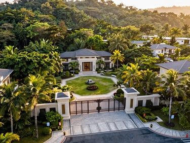 Wide-angle drone perspective of a massive premium lot surrounded by lush tropical forest and high-end security gate in a luxury community