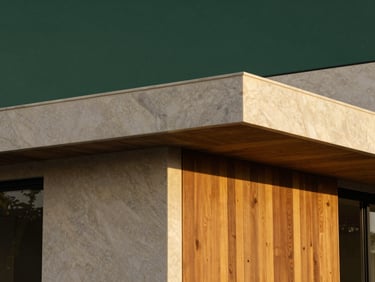 Architectural close-up of a premium minimalist villa exterior featuring travertine marble, warm wooden panels, and soft evening lighting