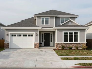 Wide exterior shot of a newly completed single-family home, front facade in natural daylight, clean trim lines and window placement, concrete driveway in foreground, no vehicles or people, overcast even light