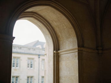 Architectural details of a historic university library stone archway, soft morning light, muted academic tones, 35mm.