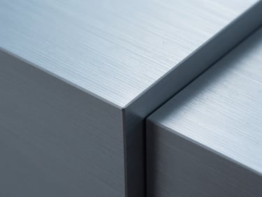 Macro detail of brushed aluminum technology hardware casing under clean cool daylight, geometric shadows