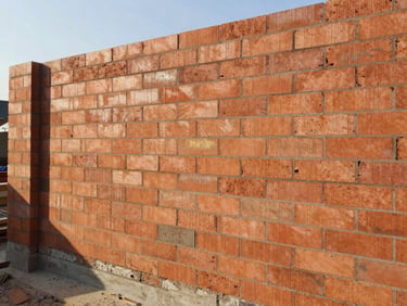 A clean residential construction site with freshly laid brick walls under bright morning sunlight, 35mm editorial photography