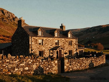 Cinematic wide-angle shot of a secluded boutique hotel nestled in Welsh hills, golden hour sunlight catching stone walls, soft shadows, 35mm film aesthetic