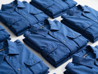 Close-up of folded tactical duty shirts in royal blue, clean organized alignment, bright natural light, 35mm