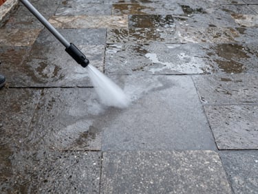 Eye-level shot of a clean stone terrace with wet flagstones after pressure washing, overcast daylight, water pooling in joints between pavers