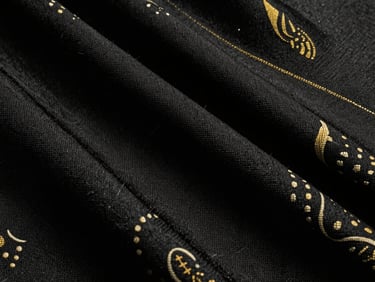 Detailed macro photography of textured Eri silk fabric, showing its dense wool-like weave, low-key lighting, deep matte black and cream tones.
