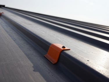 Tight macro shot of clean metal roof-line seams against a bright sky, high-contrast daylight, sharp industrial focus.