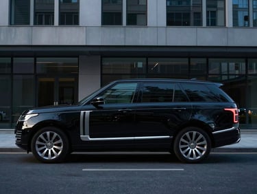 Unmarked black executive SUV parked discreetly outside a modern corporate building, early morning light, cool tones, sharp focus.