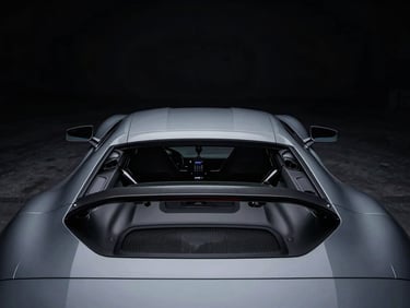 High-contrast cinematic shot of a luxury sports car, low-key lighting, sharp lines, mechanical precision, deep blacks and cool grays, off-center composition, wide environmental shot.