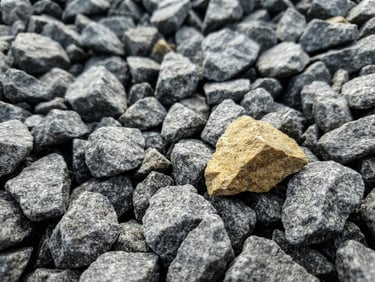 Extreme close-up of sharp, angular 20mm grey aggregate stones, high-contrast natural daylight, gritty industrial texture.