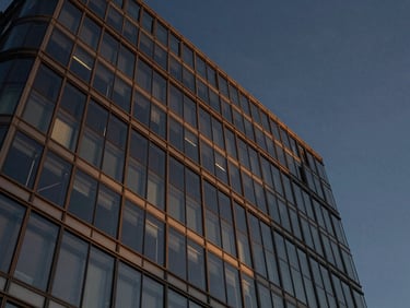 Low angle shot of modern glass skyscraper facade against deep twilight sky, clean architectural lines, sharp details, 35mm