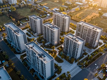 Aerial view of a master-planned modern green development plot, golden-hour sunlight casting long shadows, clean grid layout, 35mm