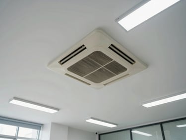 Wide angle of a commercial ceiling cassette AC unit installed in a clean office space, fluorescent daylight, neat cable trunking