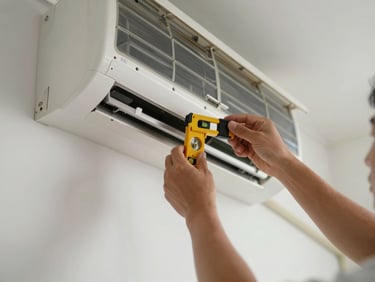 Close-up of technician hands mounting an indoor AC unit bracket on a clean wall, bright daylight, level spirit tool visible