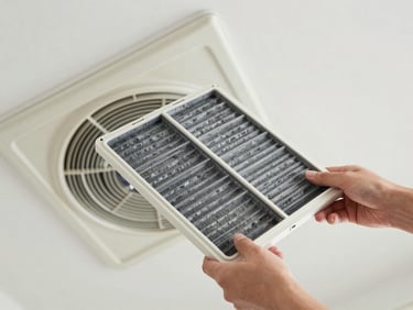 Overhead shot of AC indoor unit filter being removed for cleaning, bright studio daylight, dust particles visible, clean hands