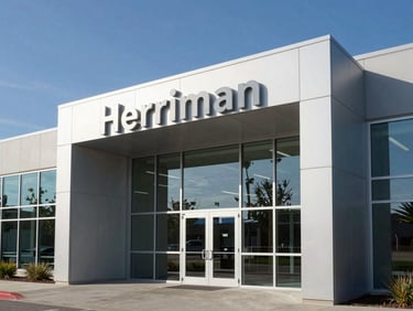 Modern steel and glass office entrance in Herriman, clean geometric brand signage reflecting the blue sky, landscape aspect.