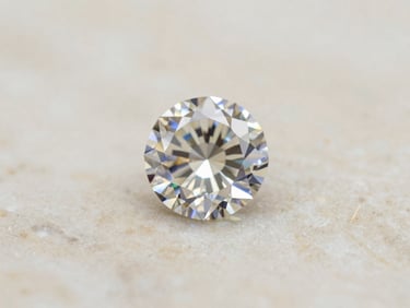 Macro shot of a brilliant-cut diamond catching sharp light on a textured ivory marble surface, soft diffused daylight, high-contrast, 35mm