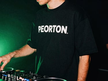 A close-up of premium streetwear fashion on a model standing near a DJ booth, neon green backlight, moody 35mm film aesthetic, high contrast.