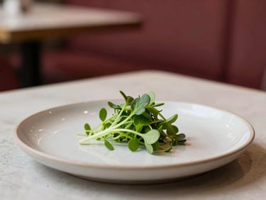 Close-up of a minimalist ceramic plate with a single micro-green salad leaf, soft side light, scandinavian restaurant interior background