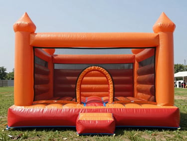 Fully inflated orange and red bounce castle staged on a flat grassy area in clean noon daylight, no occupants, front view showing the entrance arch and netting panels clearly
