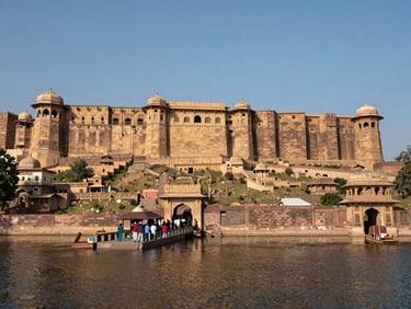 Wide shot of a fort and lake in Rajasthan, a group of tourists visible near the entrance, daylight, blue sky, sandstone walls