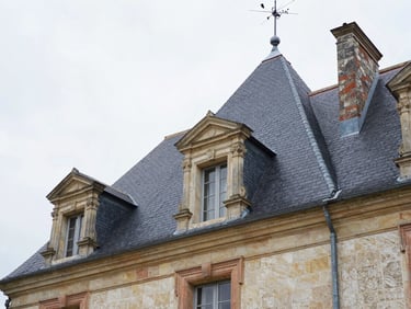 Low-angle shot of a grand French country house with a newly completed dark slate roof, soft overcast light, sharp architectural details