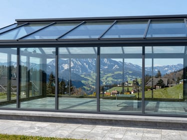 Wide architectural shot of a modern conservatory with large, clean glass panels, reflecting the surrounding Swabian Alb landscape, bright natural daylight, sharp contrast, cool blue tones