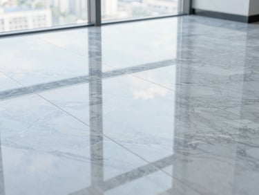 Close-up shot of the same grey marble floor, now polished to a high-gloss mirror finish reflecting a bright window, pristine and spotless