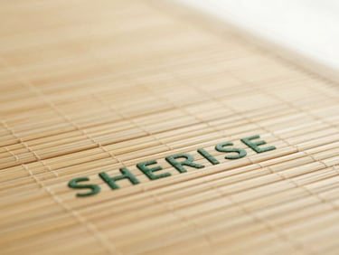 Close-up macro shot of the dry surface texture of a SHERISE bamboo pad, warm diffused side-lighting, muted silk cream and deep forest green tones.