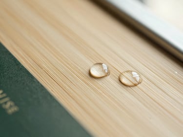 Close-up macro shot of water droplets absorbing instantly into a SHERISE bamboo fiber surface, warm diffused side-lighting, muted silk cream and deep forest green tones.