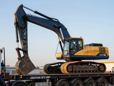 Heavy construction excavator secured on a JONATHAN'S SON INC flatbed trailer, pristine condition, crisp morning daylight, industrial editorial photography.