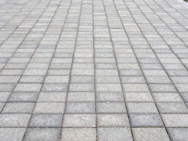 Detail shot of freshly laid block paving with clean joints and proper drainage, bright overcast daylight, 35mm.