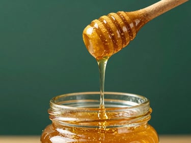 Close-up of golden honey dripping from a wooden dipper into a clear glass jar, with a subtle honeycomb pattern in the background, soft golden light, luxurious editorial photography, rich royal green and warm gold accents, high-contrast textures, 35mm