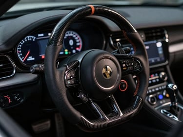 Moody close-up of a carbon fiber steering wheel and digital dashboard inside a high-end performance vehicle, dramatic low-key lighting, 35mm lens